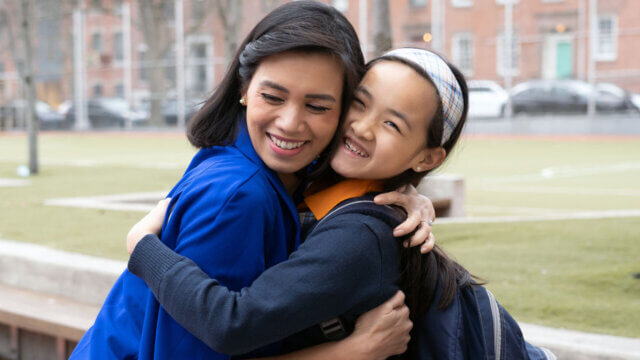 Two people hugging outdoors on a school playground.