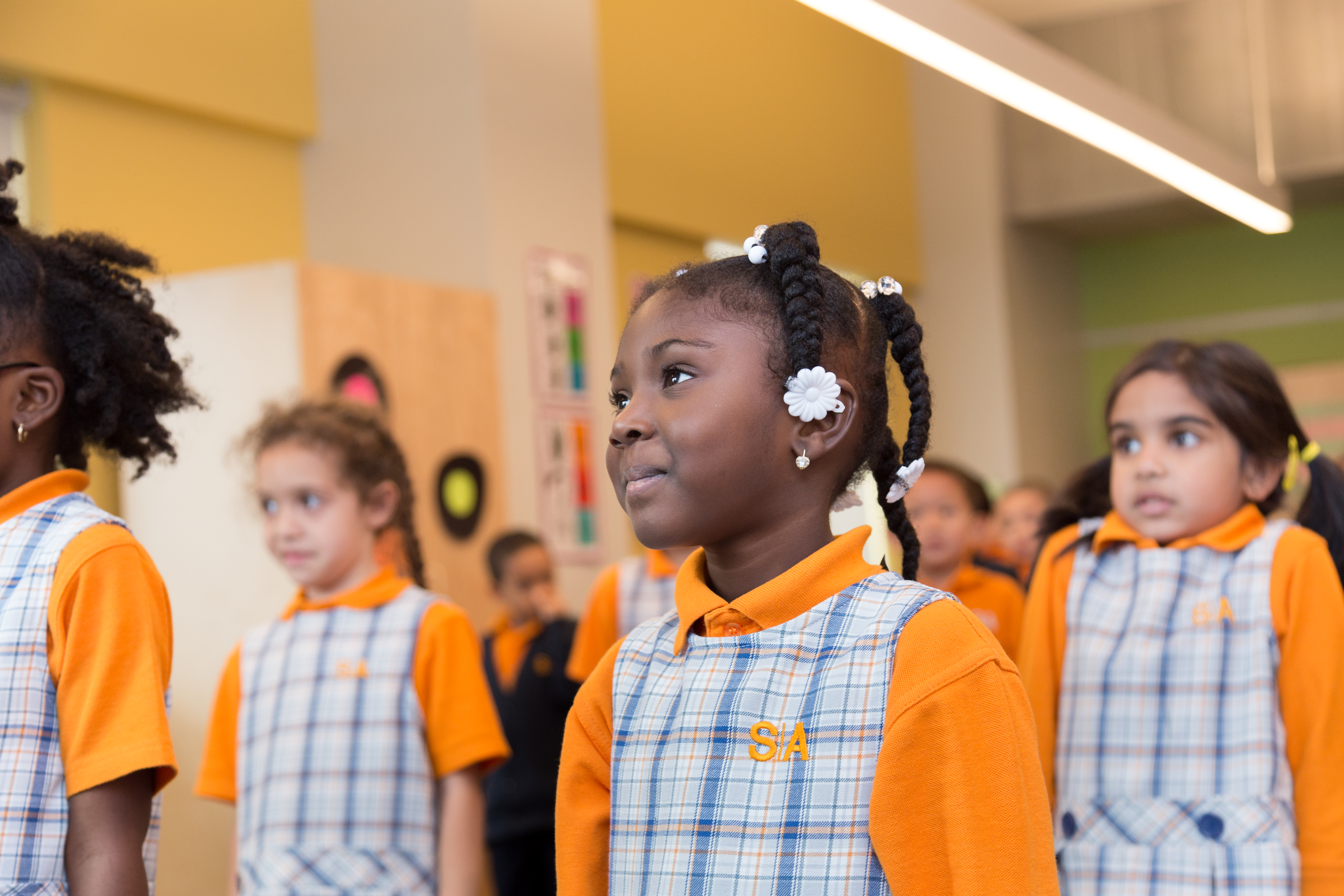 Students standing up in a classroom wearing Success Academy uniforms.
