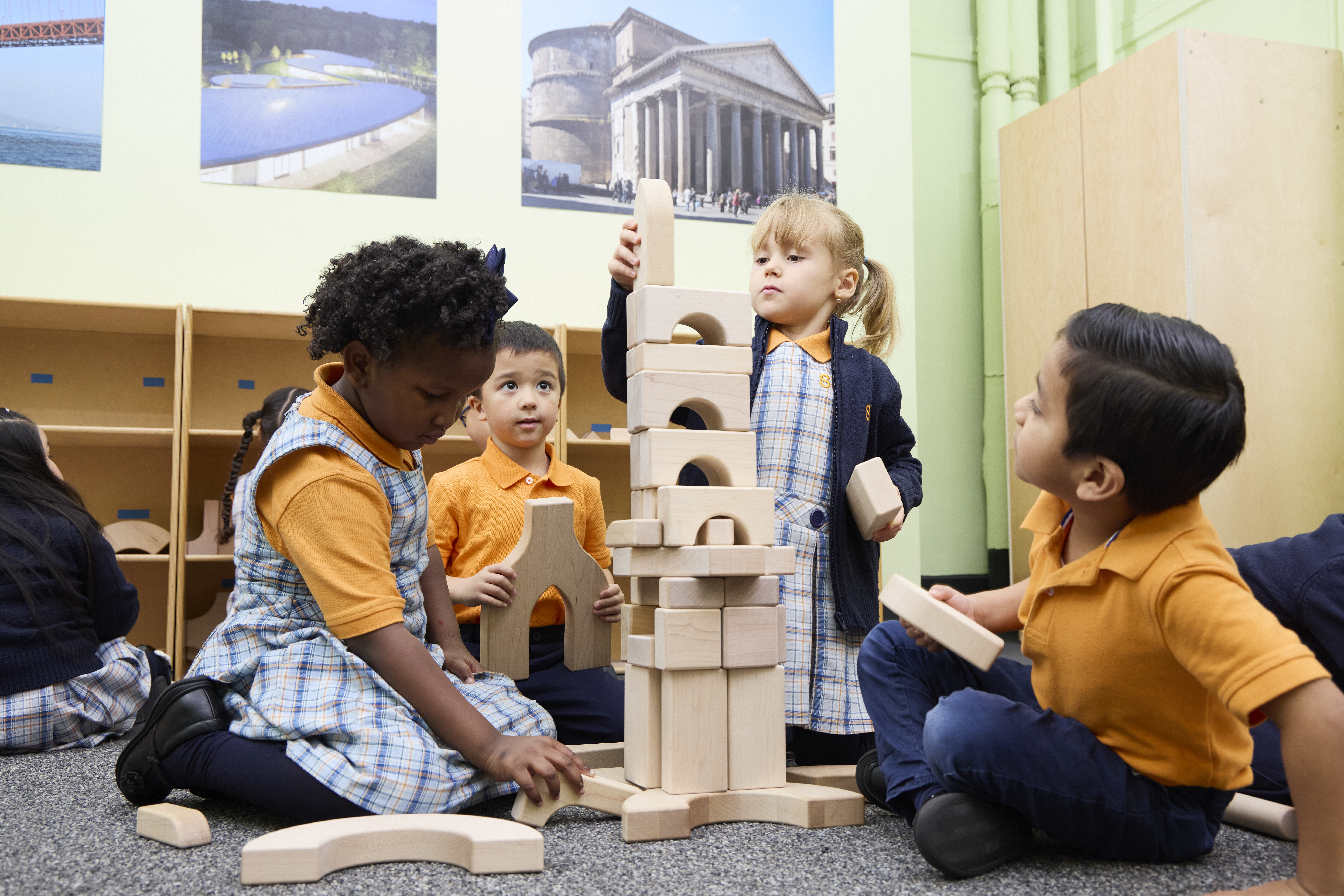 Children building a tower with wooden blocks in a classroom.