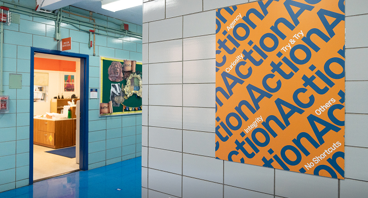 Interior hallway view of a brightly colored Success Academy school with a poster featuring the word 